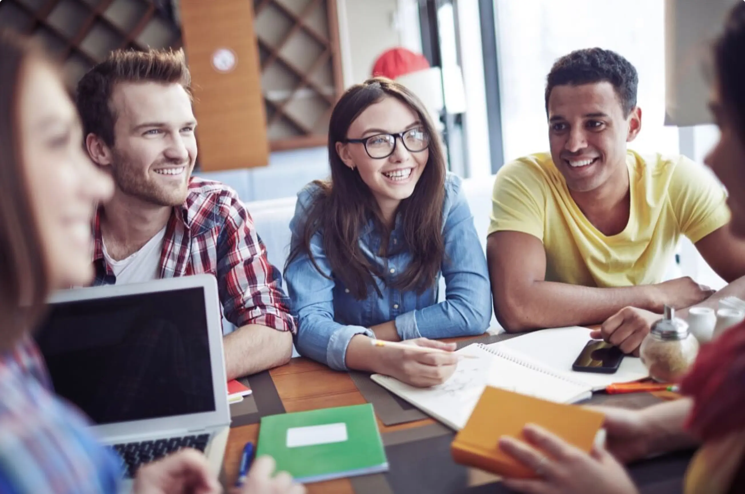 zwei Frauen und zwei Männer, die an einem Tisch sitzen lachen und arbeiten